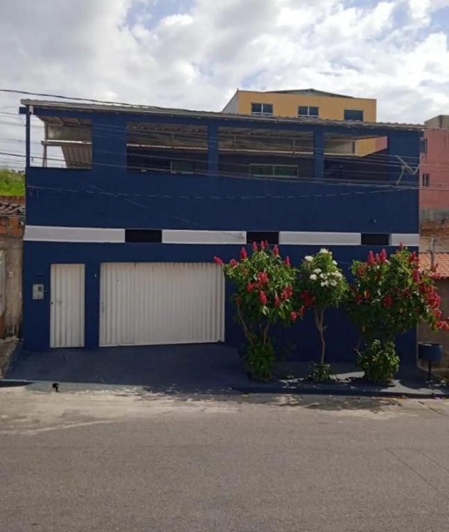 a blue building with two garage doors and flowers at Casa familiar in Vespasiano