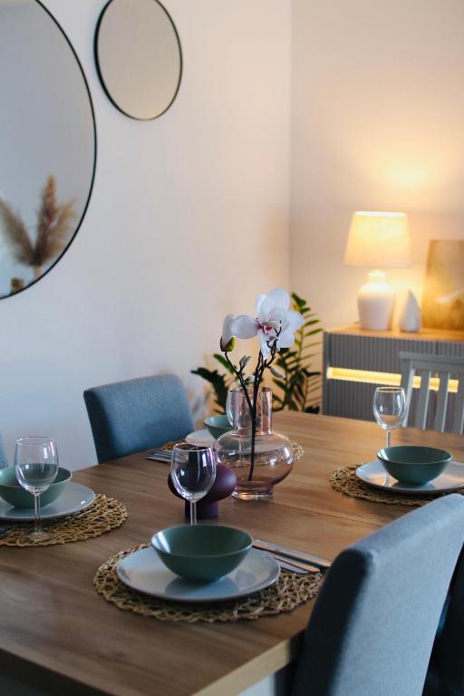 a wooden table with plates and wine glasses on it at Łeba Garden Apartament in Łeba