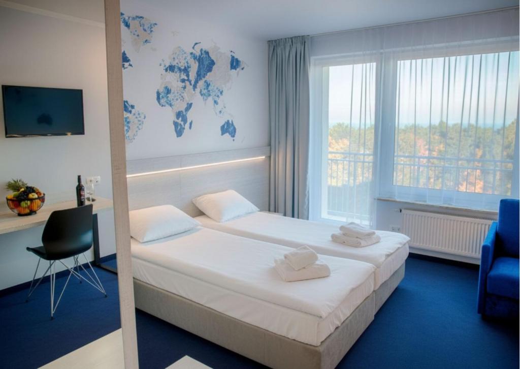 Bright twin-room with two made beds, folded towels, world-map wall art, desk with fruit bowl.