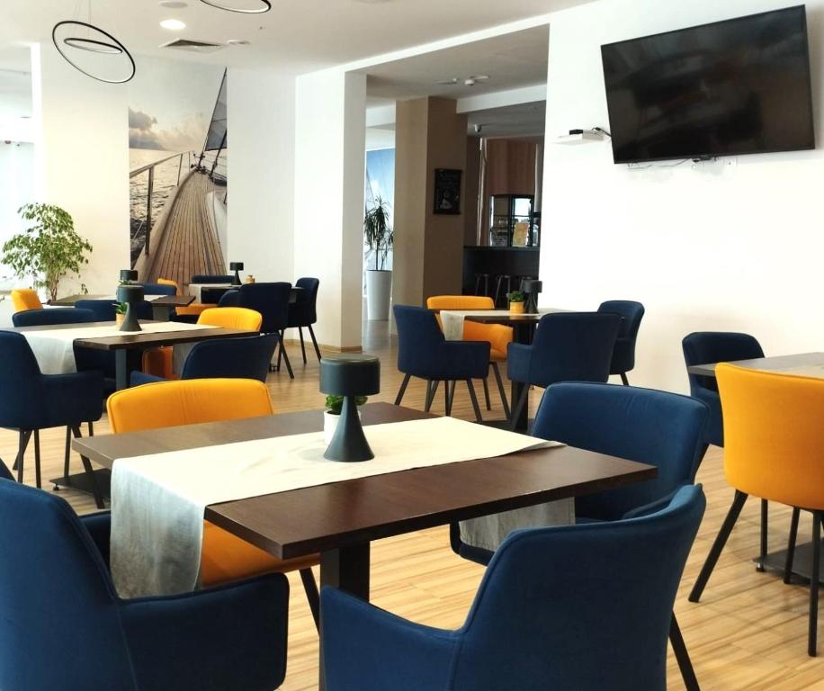 Contemporary dining room with blue and yellow chairs, wooden tables, wall TV and nautical mural.