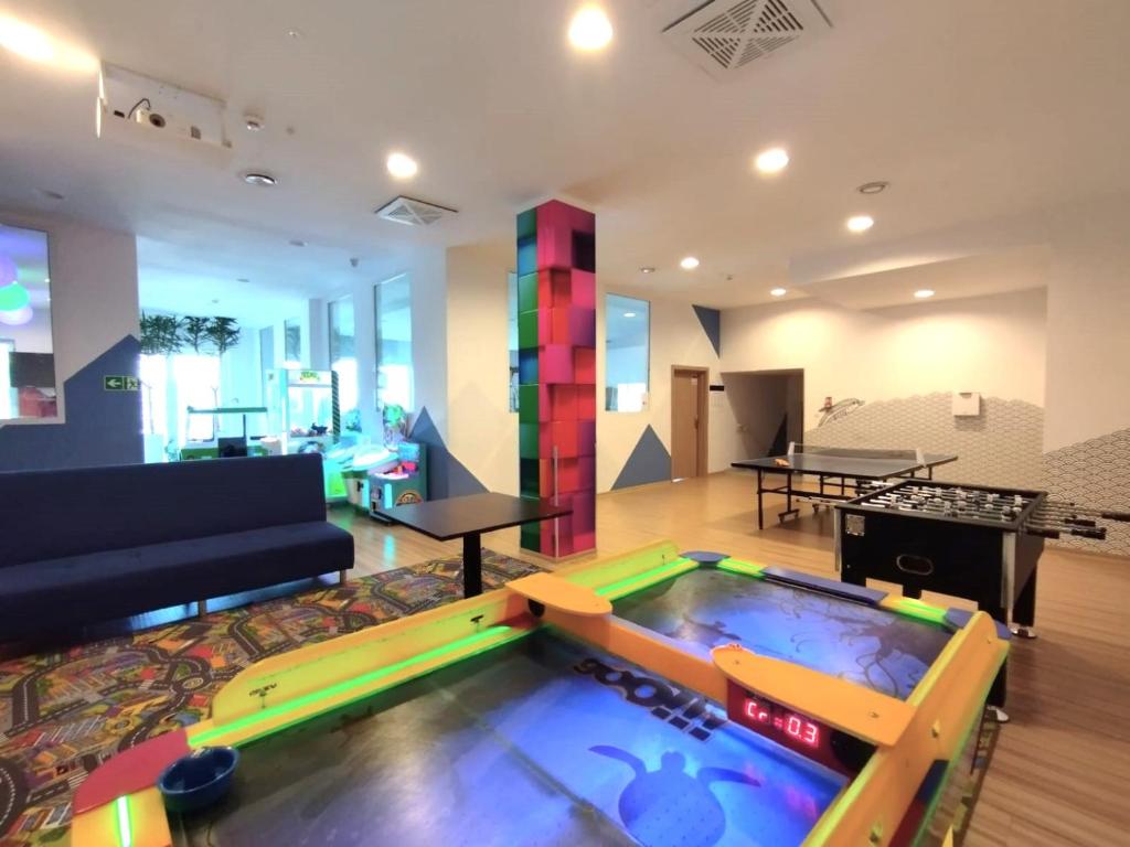 Colorful game room with air hockey, foosball, ping-pong table, seating, and playful lighting.