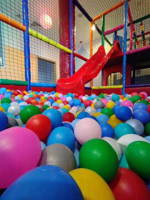 Ball pit filled with multicolored plastic balls and a red slide, low-angle playful perspective.