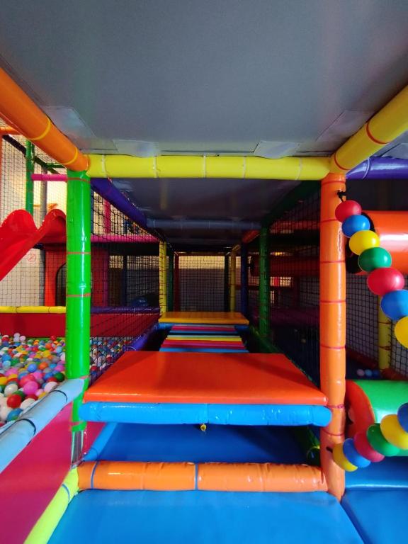 Interior soft-play tunnel featuring padded colorful platforms, netted sides, and ball pit glimpses, adventurous play space.