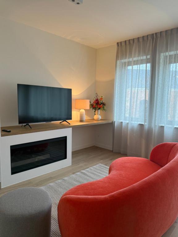a living room with a red chair and a flat screen tv at L'Excelsior Suites in Brasschaat
