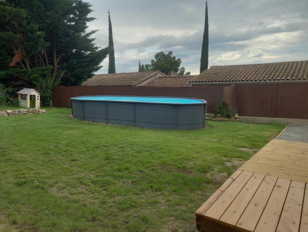 a backyard with a swimming pool in the grass at maison 2 ch confortable in Saint-Montan