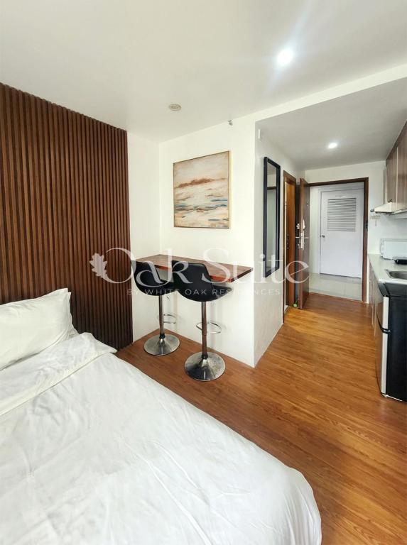 a bedroom with a bed and a table and a kitchen at Oak Suite in Baguio