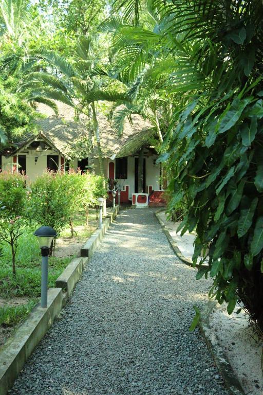 a house with a pathway leading to a yard at Greenbay Beach Resort in Varkala