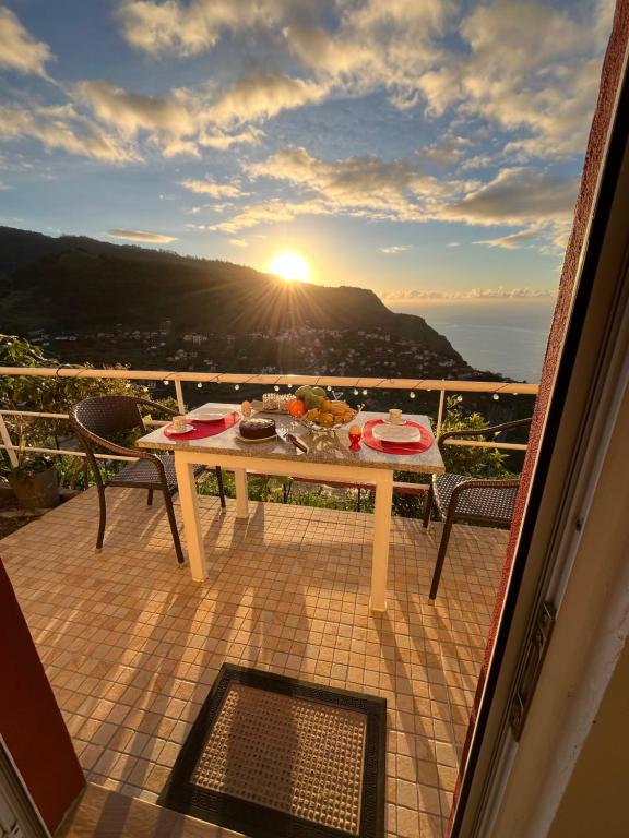 a table and chairs on a balcony with the sunset at Tropical House in Ribeira Brava