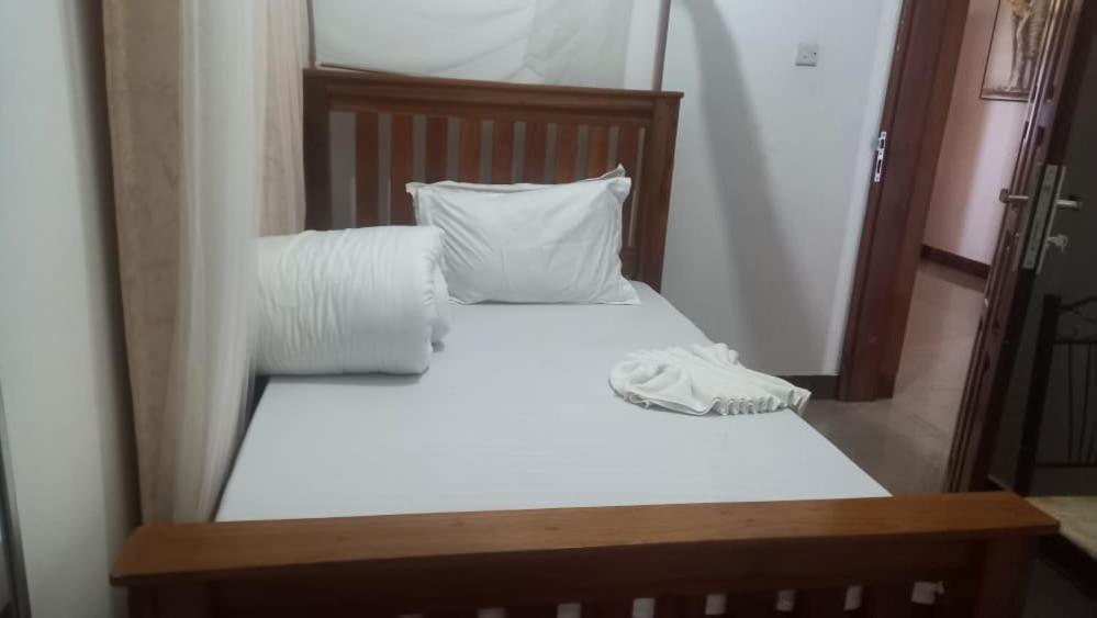 a bed with white sheets and pillows in front of a mirror at GcAnnexLodge in Iringa