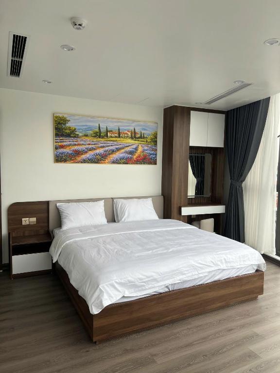 a bedroom with a large bed with a painting on the wall at Sora Hotel in Thường Son