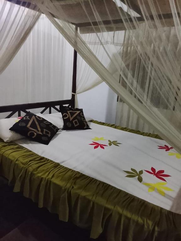 a bed with a white comforter with flowers on it at peacock Rest in Batapola