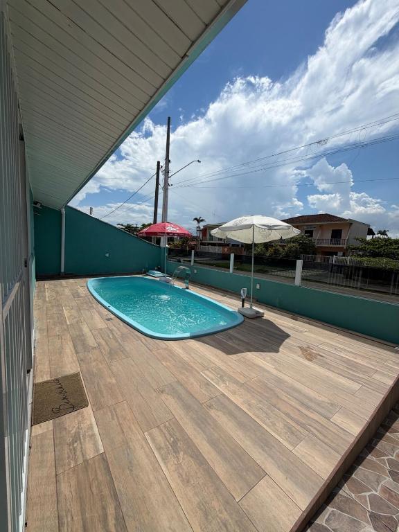 a swimming pool on a patio with an umbrella at Casa em Ipanema - Pontal do Paraná in Pontal do Paraná