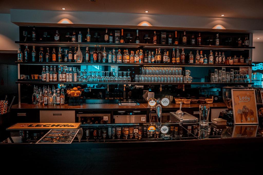 Dimly lit hotel bar with shelves of liquor bottles, glassware and beer taps on counter.