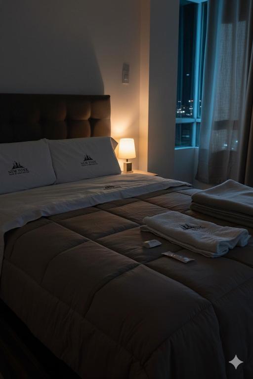 a bedroom with a large bed with a lamp and a window at Hostal New York in Jauja