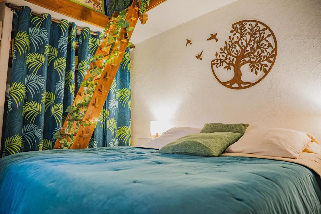 a bedroom with a blue bed with a tree mural at La Suite de Richarville in Richarville