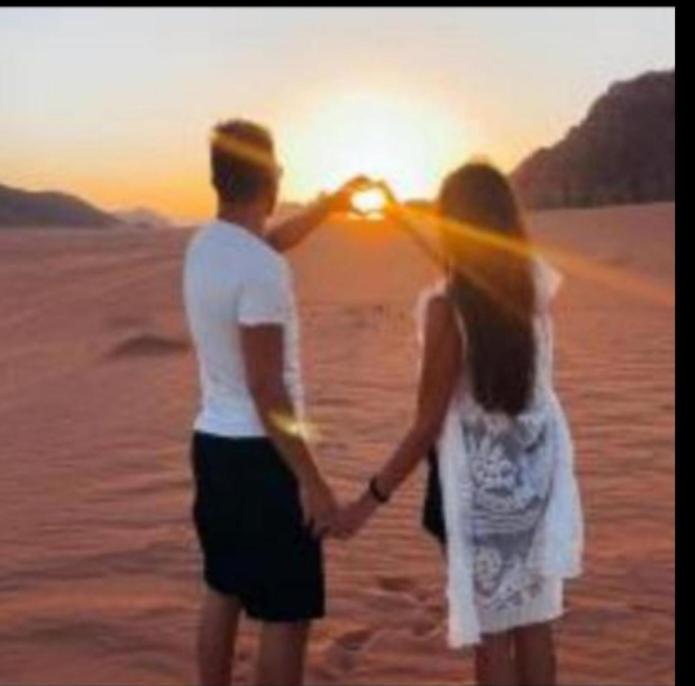 a man and a woman standing in the desert holding hands at Camp in Wadi Rum in Maḩaţţat Dīsah