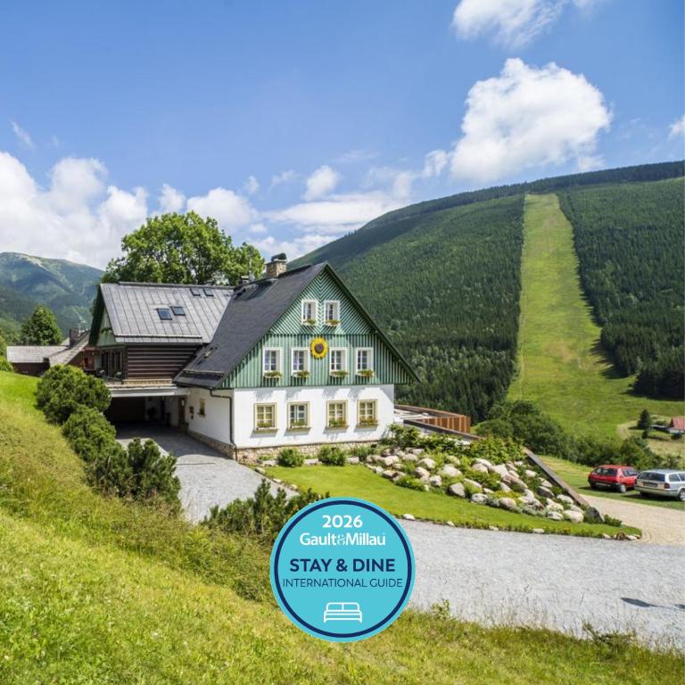 a house on a hill with a sign in front of it at Pension Slunečnice & Panorama Restaurant Farma in Špindlerův Mlýn