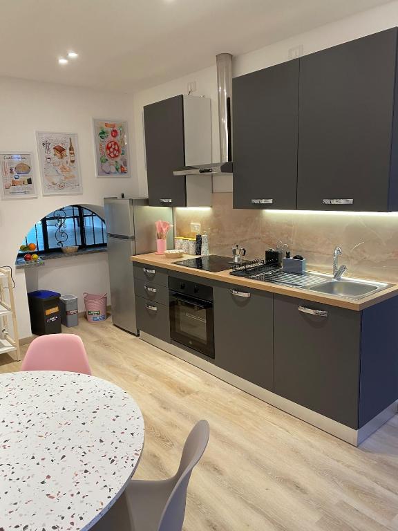a kitchen with black cabinets and a table with chairs at Casa MELISSA LIMONCELLA , free parking-self check in in Tavernerio