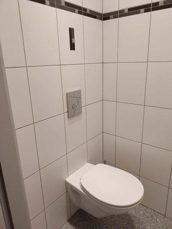 a white toilet in a white tiled bathroom at Gîte d'ammerschwihr in Ammerschwihr