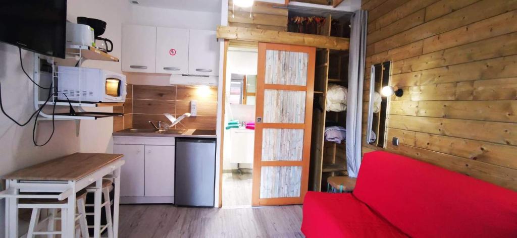 a living room with a red couch and a kitchen at L'Escale Balnéaire Landaise in Biscarrosse-Plage