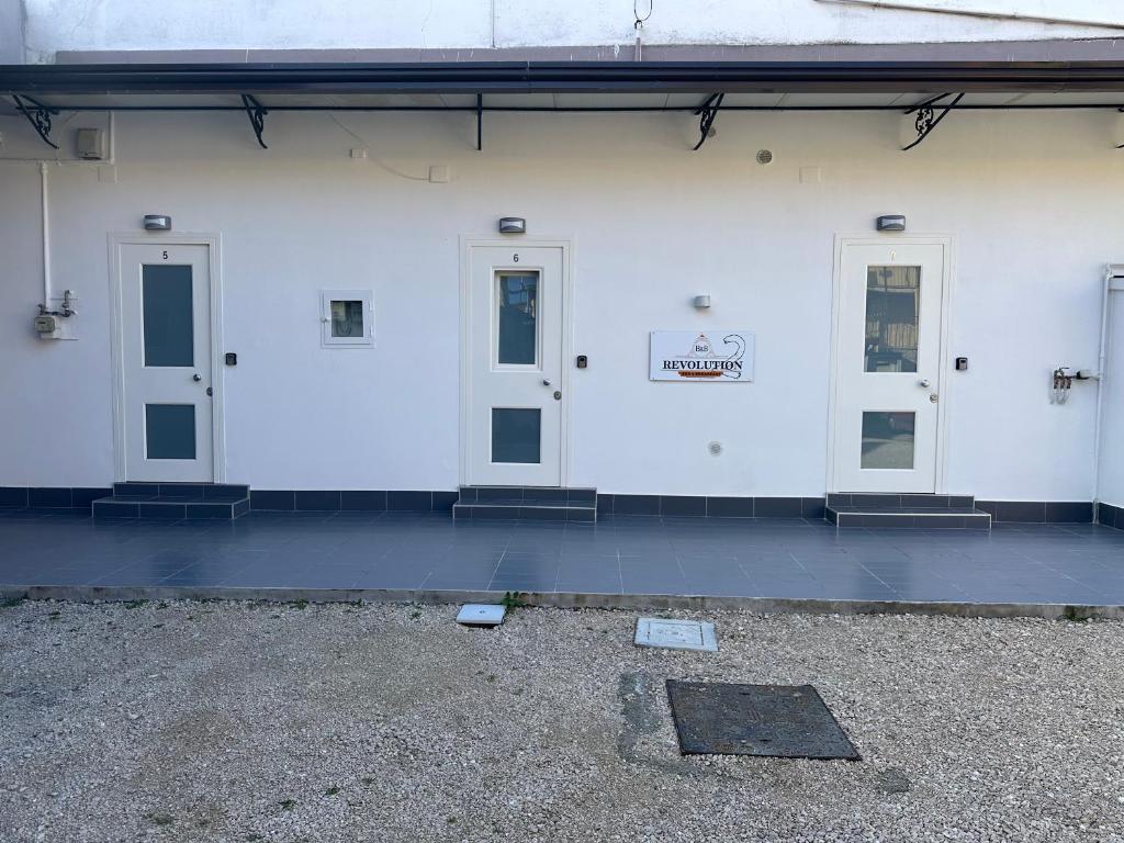 a white building with three doors and a sign on it at B&B REVOLUTION 2 BED e BREAKFAST in Caserta