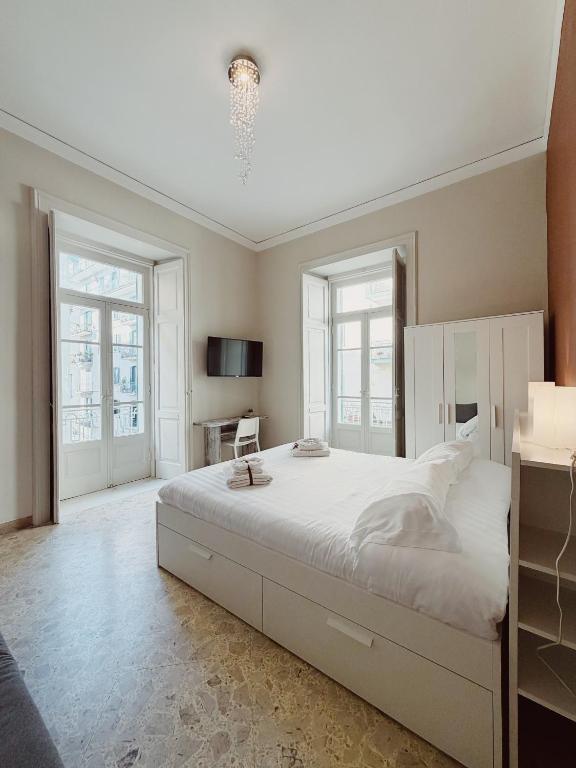 a bedroom with a large white bed and two windows at Diaz Central Rooms in Salerno