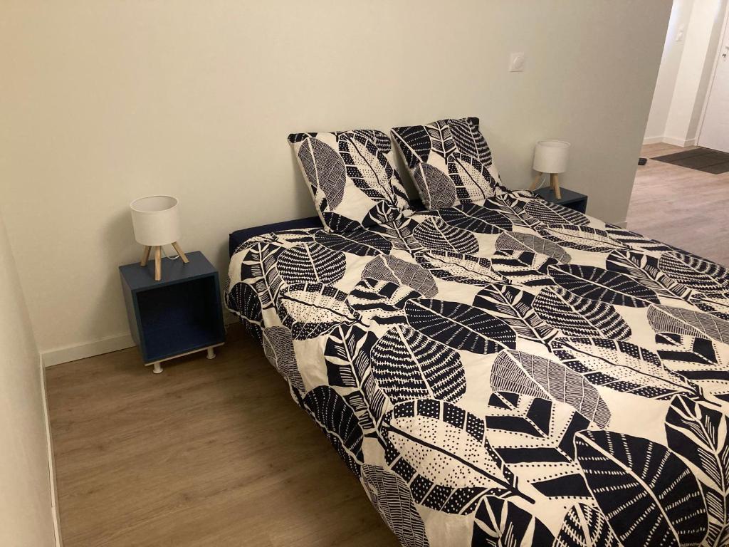 a bedroom with a bed with a black and white comforter at Grande chambre indépendante in Bruz