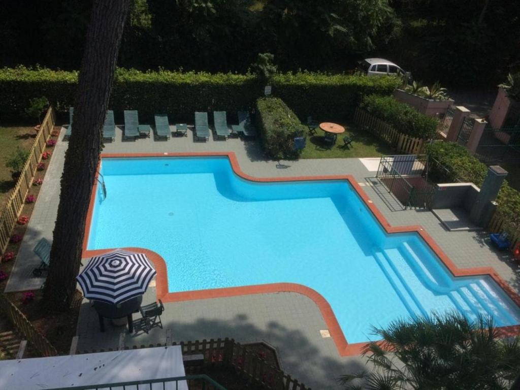 a large blue swimming pool with an umbrella and chairs at Lightblue in Marina di Massa
