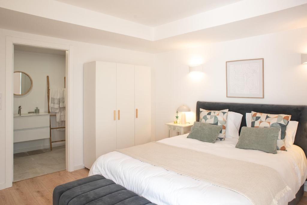 a white bedroom with a large bed and a chair at Relax House in Estoril