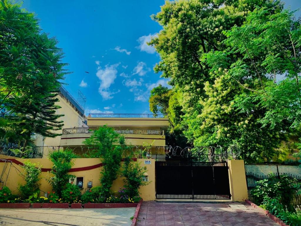 a yellow building with a black gate and trees at Executive Royal Garden in Islamabad