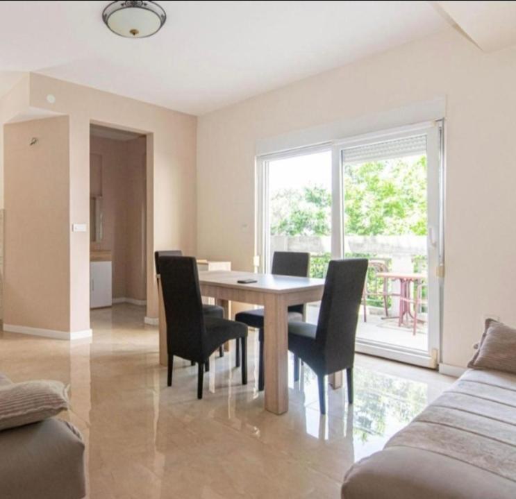 a dining room with a table and chairs and a window at Topla in Herceg-Novi