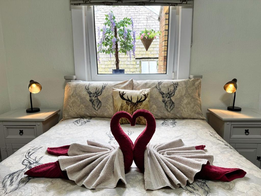 two hearts are sitting on a bed with towels at The Sandbed Retreat in Hawick