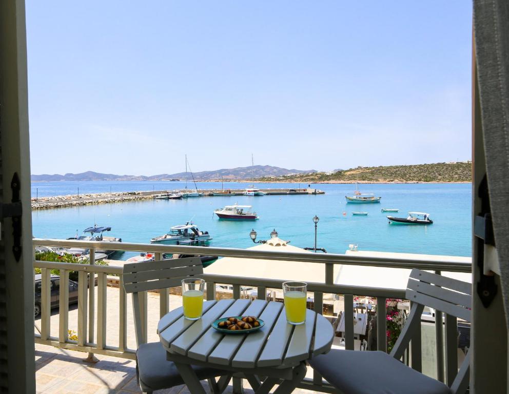 a table with a plate of food on a balcony with a harbor at Angeliki Seaside Hotel in Aliki