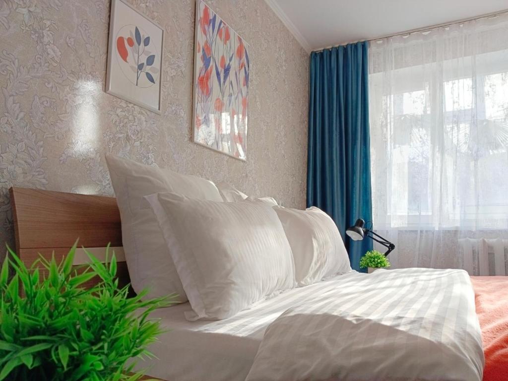 a bedroom with a bed with white sheets and a window at 11 Microragion in Aktobe
