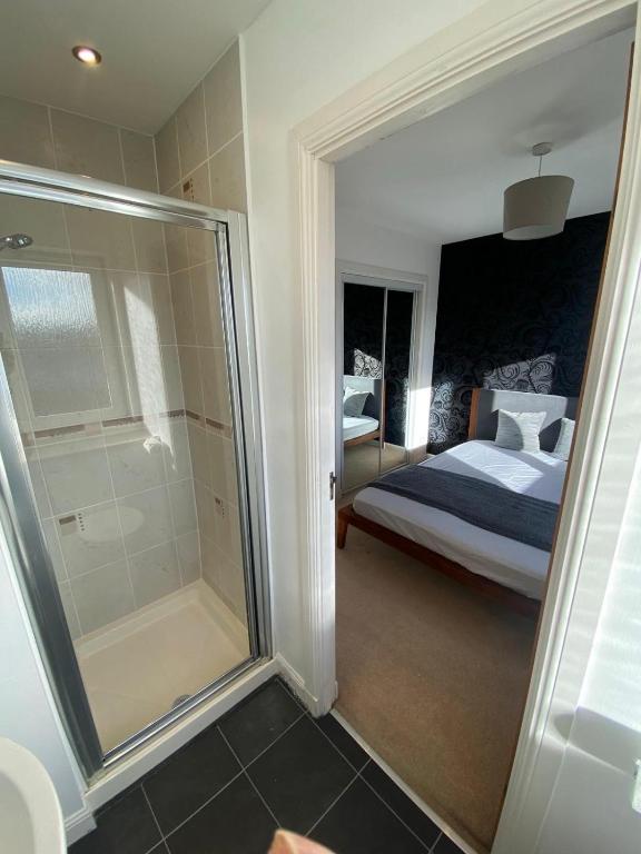 a bedroom with a bed and a glass shower at One double en-suite room at seaside flat in Aberdeen
