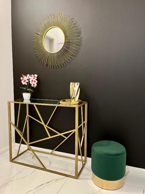 a gold console table with a green stool and a mirror at Interno Casa in Sopron