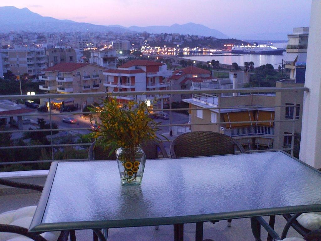 un vase en verre avec des fleurs sur une table sur un balcon dans l'établissement Rafina Port Paradise, à Rafína