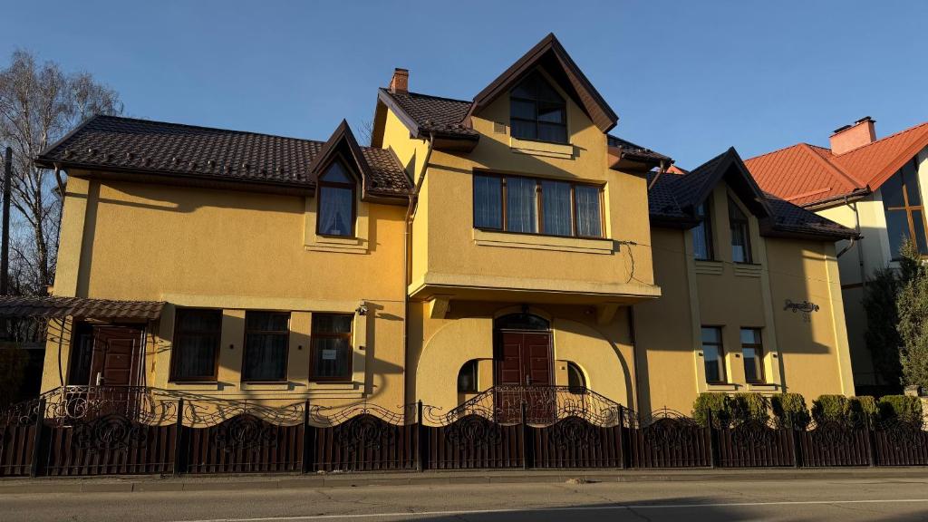 a large yellow house with a black fence at Luxury Apartaments 3 in Truskavets