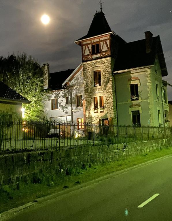 an old house with a clock tower on the side of a street at L'ECURIE du Château in Lebétain