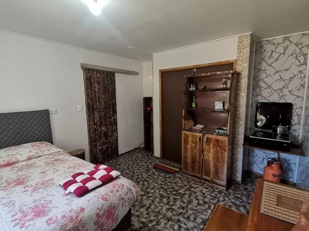 a bedroom with a bed and a table and a tv at tiny house kiñeco melipeuco conguillio in Santa María