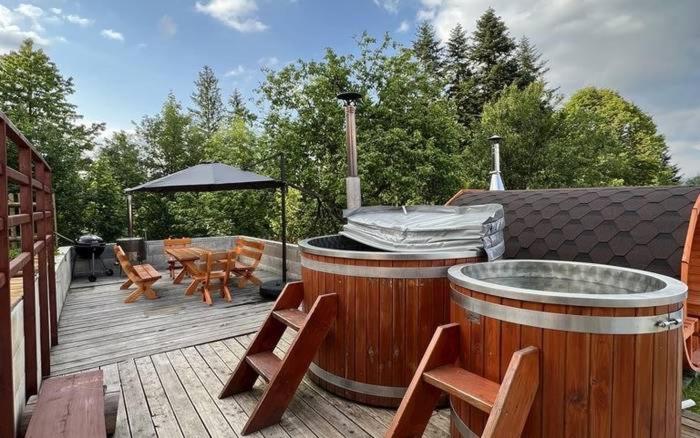 a hot tub on a deck with chairs and an umbrella at Wellness chata Kozička in Klokočov