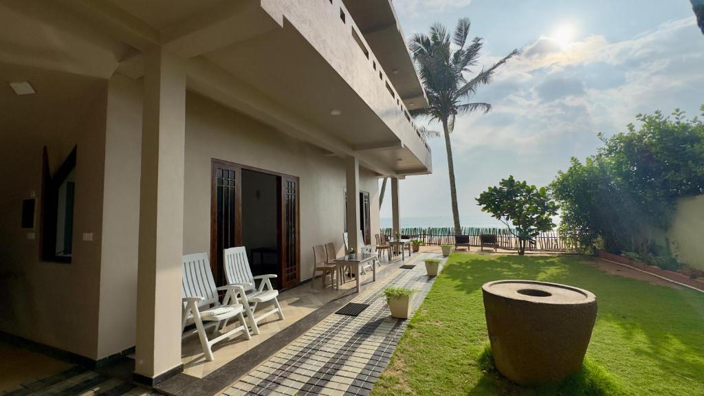 a patio of a house with chairs and a lawn at Vacation Beach in Hikkaduwa
