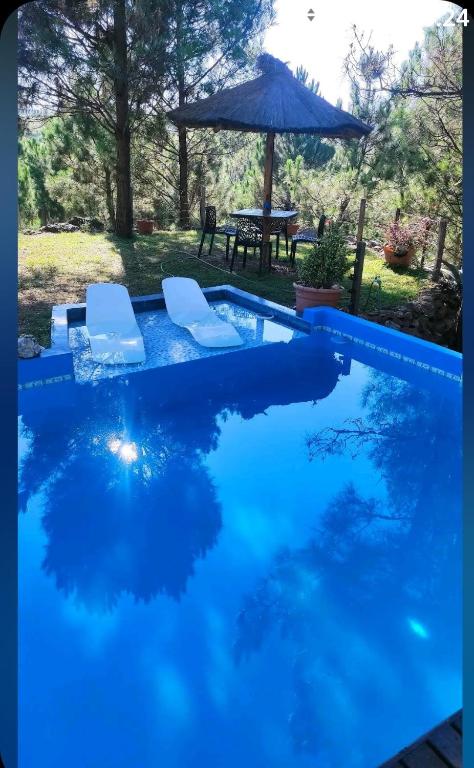 a blue swimming pool with two chairs and an umbrella at Tierra Nuestra in Villa Ciudad de América