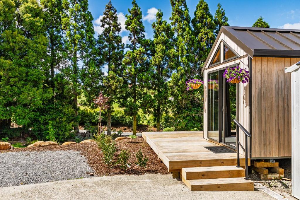 a small cabin with a wooden ramp in a garden at Tiny on Access in Kerikeri