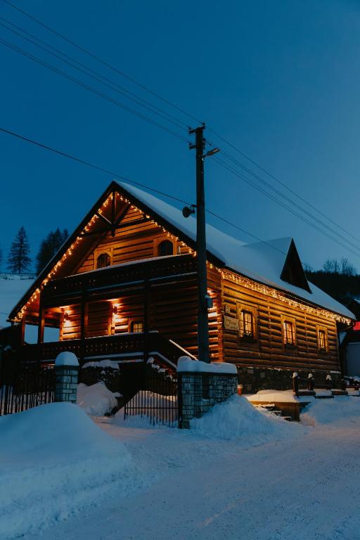 a log cabin in the snow at night at Granddrevenica in Malá Franková