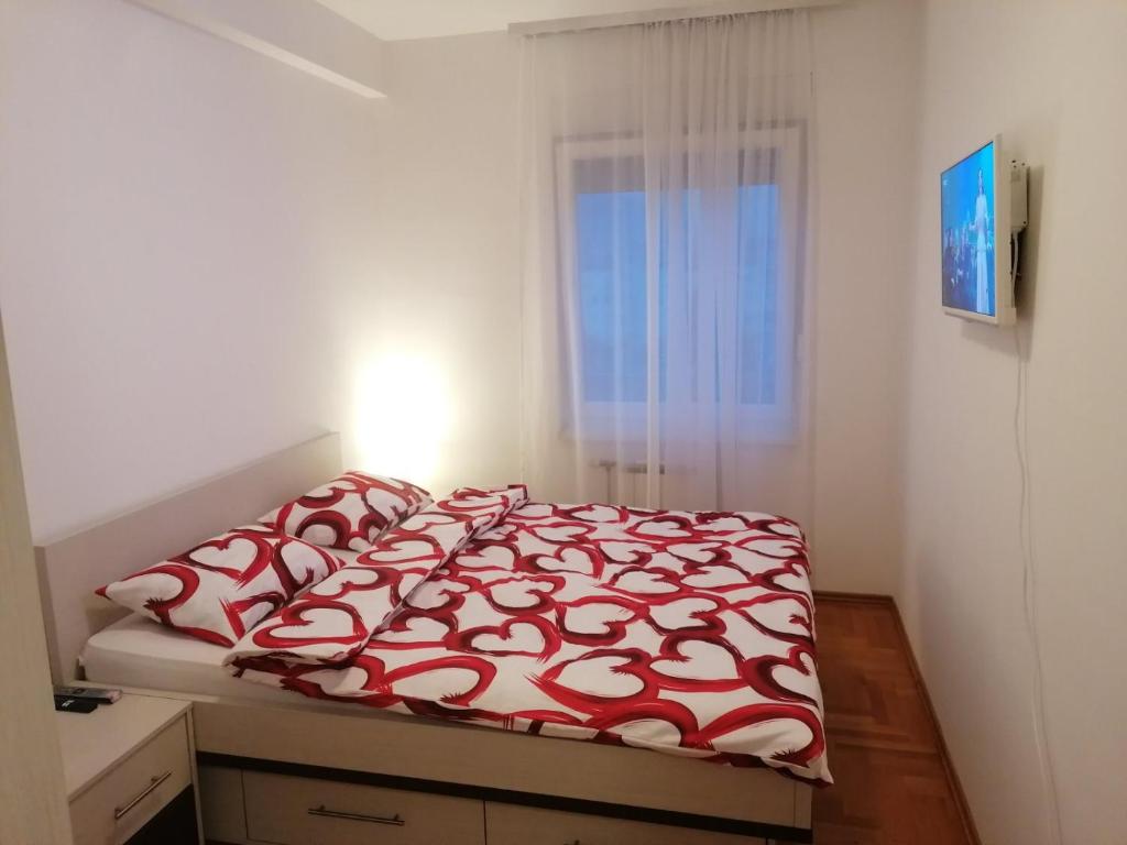 a bedroom with a bed with a red and white comforter at Apartman 44, sa garažom, Mejdan Banja Luka in Banja Luka