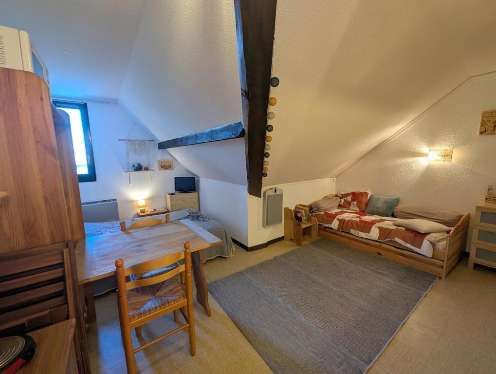a attic room with a bed and a table at Studio pied des pistes in Réallon