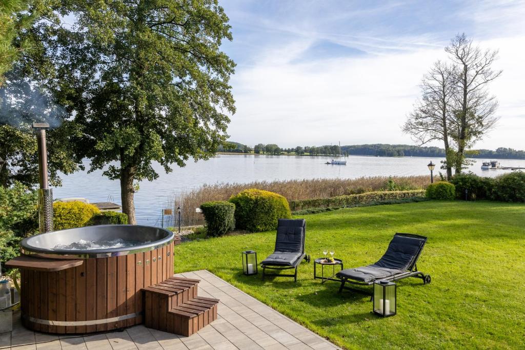 a hot tub in the grass next to two chairs at Family Lake House in Mikołajki