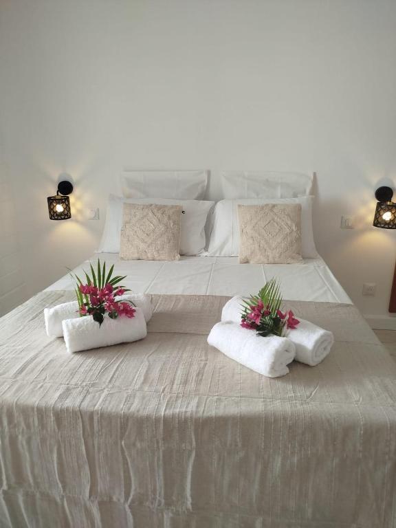 a large white bed with two pillows and flowers on it at Logement chic au style tropical contemporain in Îlet à Christophe