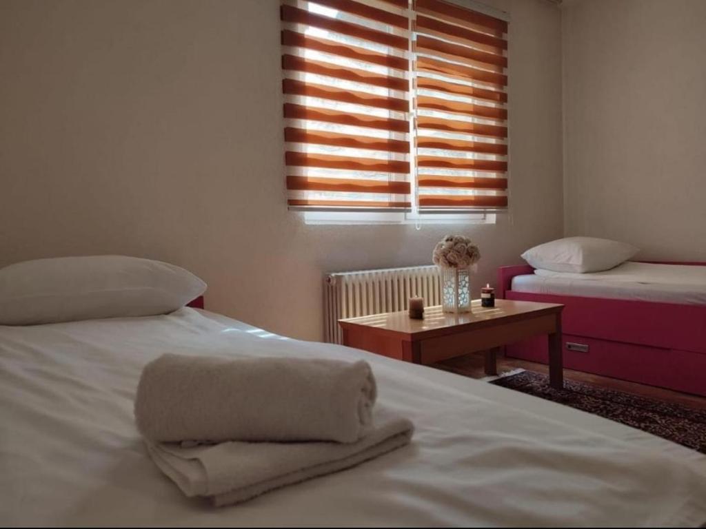 a bedroom with two beds and a table with a window at Pandora Apartments Sarajevo in Sarajevo